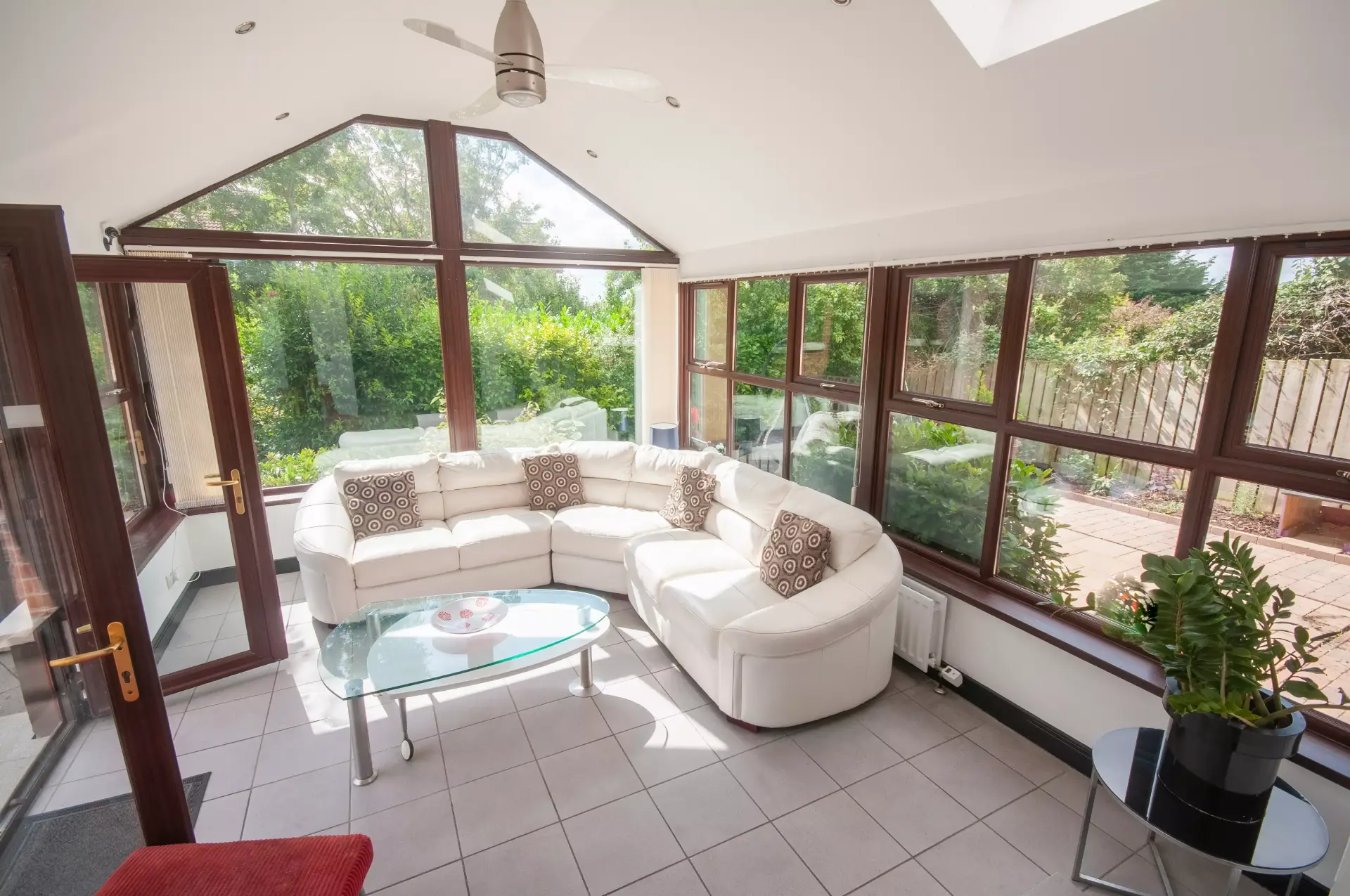 A bright conservatory with a cream sectional Ceiling fan