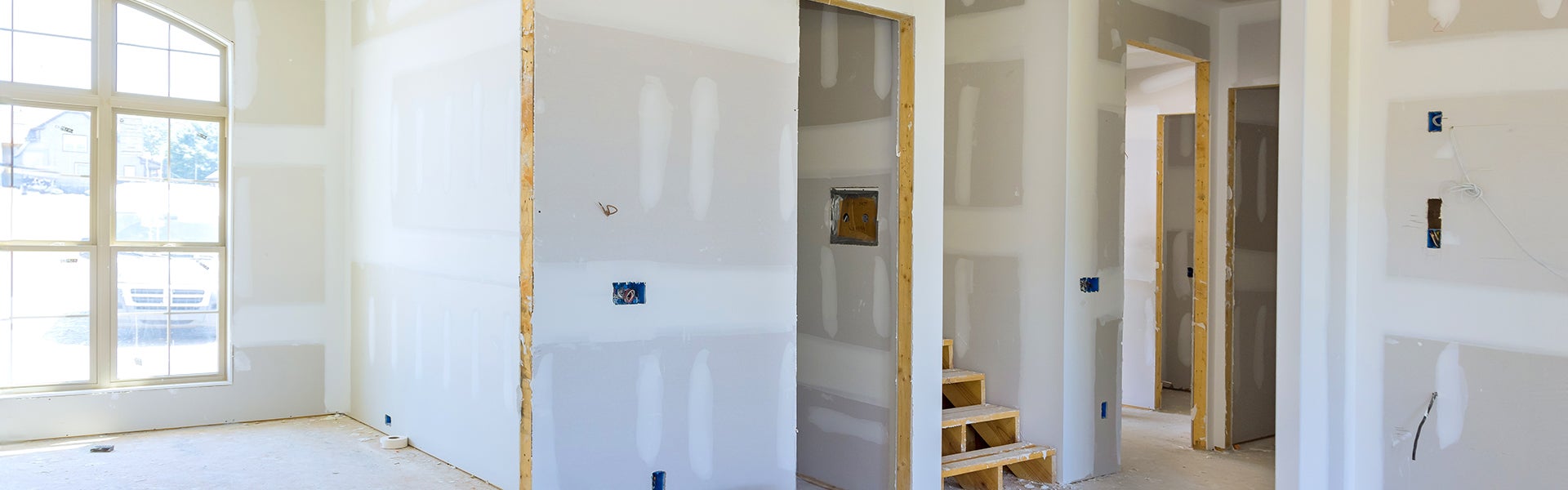 Interior of a house under construction with unfinished drywall, exposed wiring