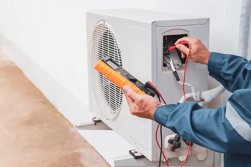 HVAC technician testing an outdoor air conditioning unit with a multimeter.
