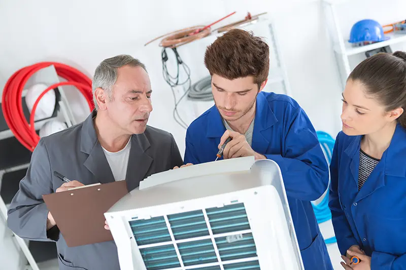Three people examining an appliance