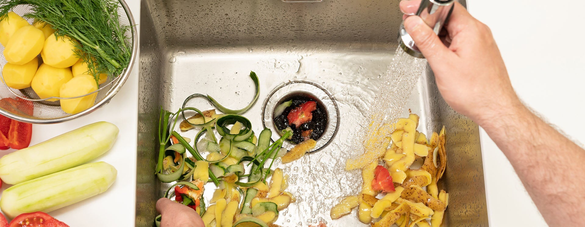 A woman and young child wash lettuce under a kitchen faucet with running water.